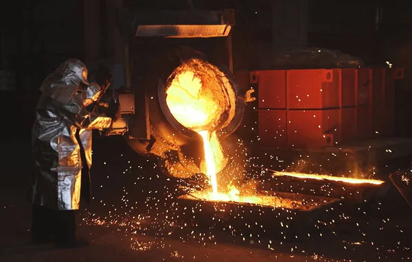 Metalurjik bir fabrikada portakal metali eritmek. Kepçeden sıvı demir.