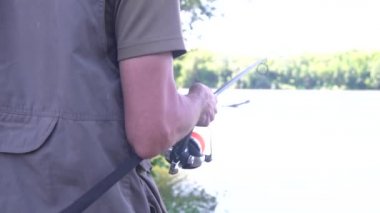 Erkek eller balık tutarken makarayı çevirir. Dönen makara yakın plan. Sazan avı