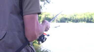 Erkek eller balık tutarken makarayı çevirir. Dönen makara yakın plan. Sazan avı