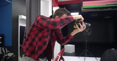 Genç yakışıklı profesyonel fotoğrafçı stüdyoda bir modelin fotoğrafını çekiyor. Ele geçirilen resimlerden memnun..