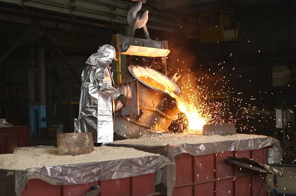 Metalurjik bir fabrikada portakal metali eritmek. Kepçeden sıvı demir.