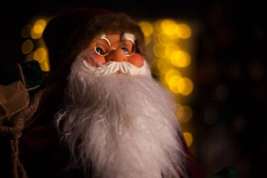 Noel Baba hediye dolu büyük bir çanta taşıyor, Noel ağacının yanında.