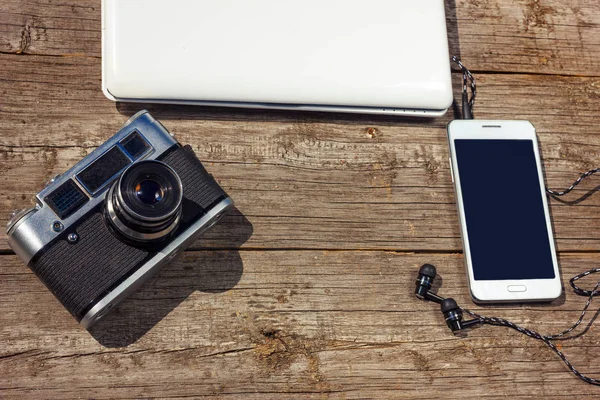 camera phone and laptop are on a wooden table