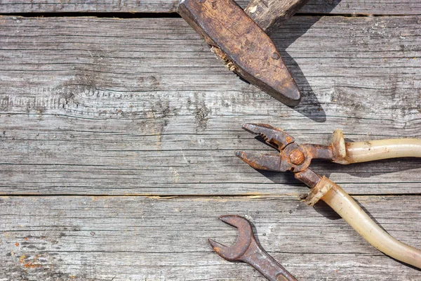 are the tools on wooden background hammer pliers and open-end wrench