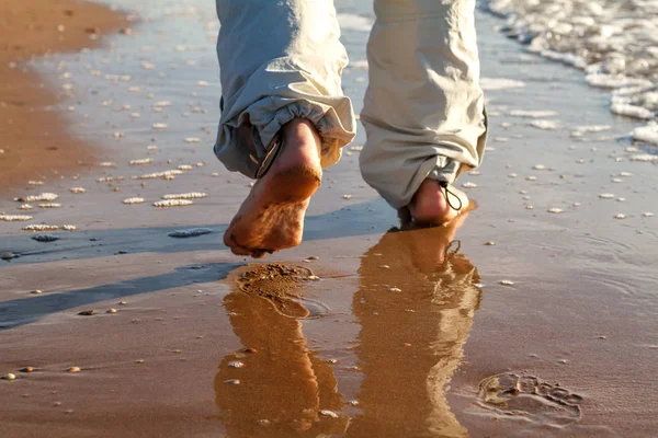 barefoot man walking on the beach vacation concept