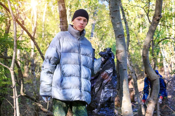 young man collects garbage in the forest