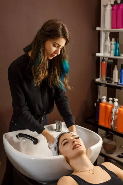 happy client in a hair salon who wash her hair with shampoo.