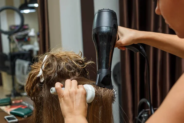 the hairdresser dries hair to the client with a Hairdryer.