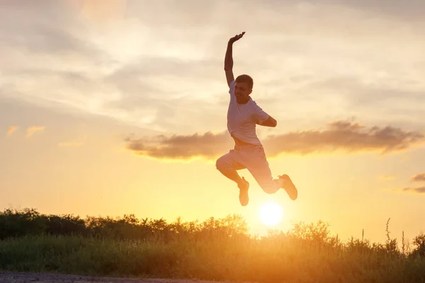 young man jumping up against the sunset sky.