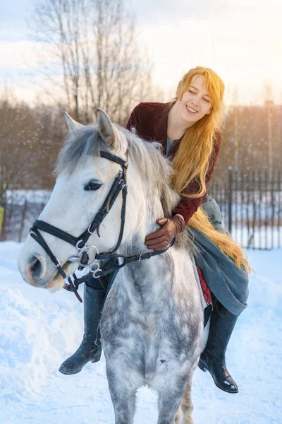 young woman with long hair with horse in winter