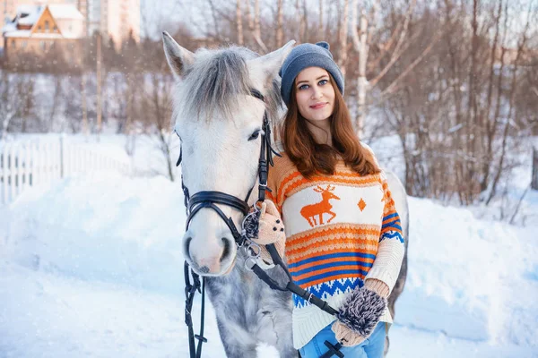 young beautiful woman in winter with beautiful white horse