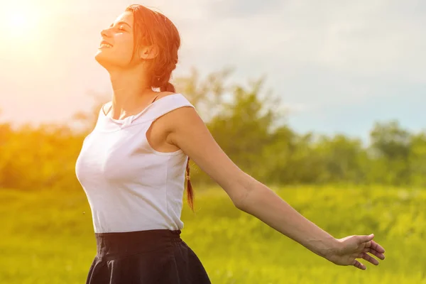 beautiful girl enjoying the sun with her arms outstretched in the field against the sky