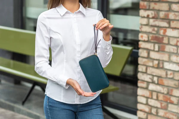 Flicka i vitt håller en vacker plånbok i handen — Stockfoto