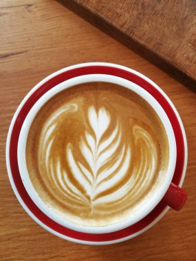 Ahşap arka planda bir fincan latte sanat kahvesi.