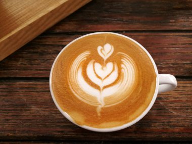 Ahşap arka planda bir fincan latte sanat kahvesi.