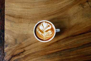 Ahşap arka planda bir fincan latte sanat kahvesi.