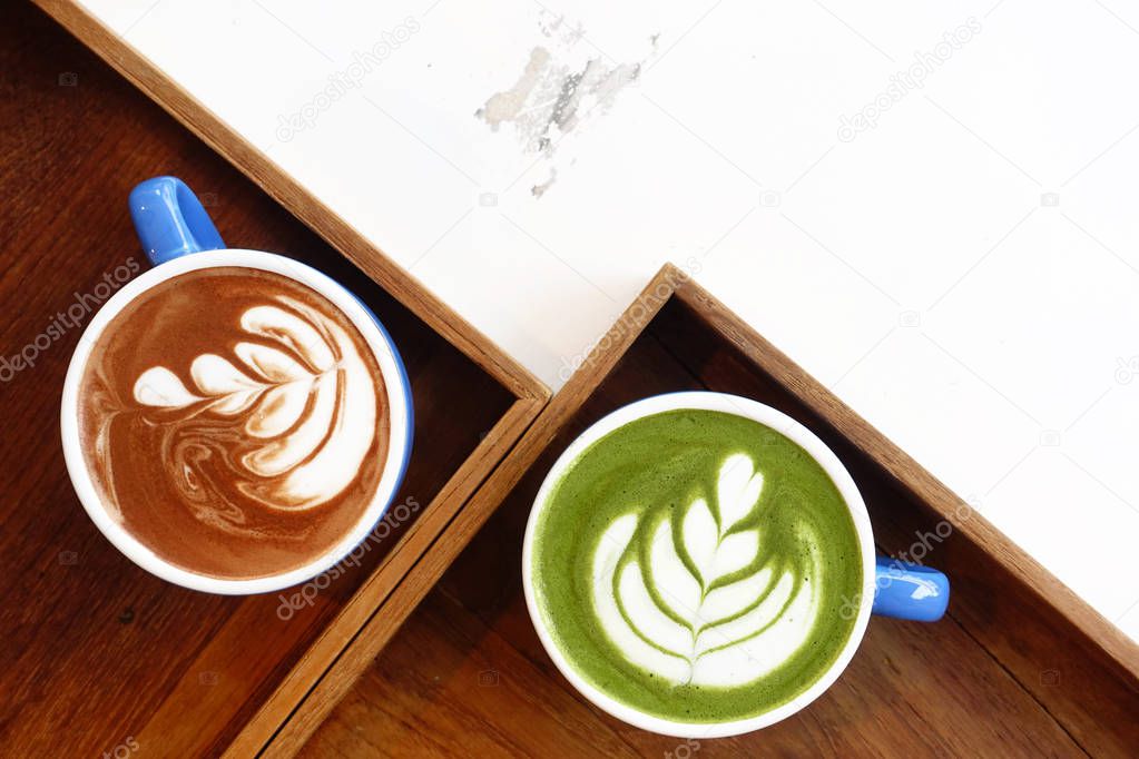 A cup of green tea matcha latte and cup of latte art coffee on wooden background