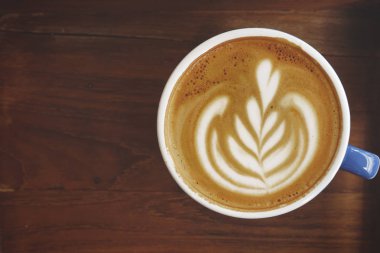 Ahşap arka planda bir fincan latte sanat kahvesi.