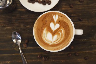 Ahşap arka planda bir fincan latte sanat kahvesi.