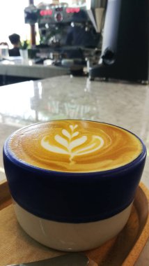 Ahşap arka planda bir fincan latte sanat kahvesi.                              