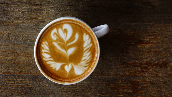 Ahşap arka planda bir fincan latte sanat kahvesi.                                                                                                                                                                                           