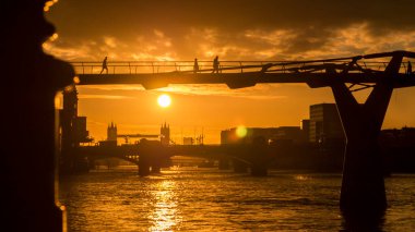 Sabahın erken saatlerinde Millennium Köprüsü ve Tower Köprüsü üzerinde insanlar işe giderken.
