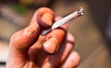 Londra, İngiltere - 25 Mart 2012: Sigara tutan kirli nikotin lekeli el. Bu sigara içmenin etkilerinden kaynaklanıyor.