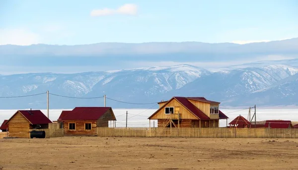 New style houses on Olkhon island. Made in wooden log style with red roof. Located nearby Baikal lake in front of mountains taken in late winter