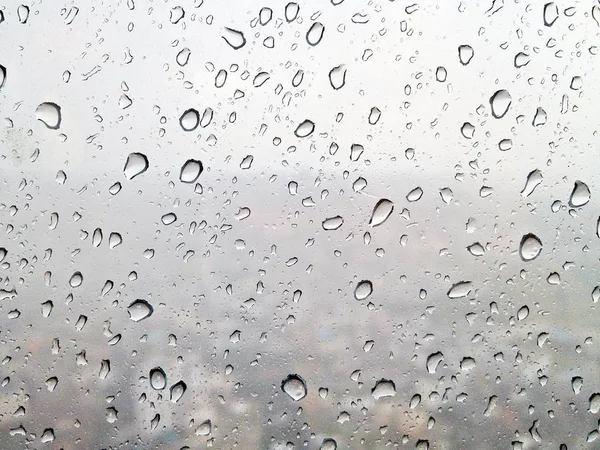 Rain drops on window glasses surface while heavy rain that seeing in blur background