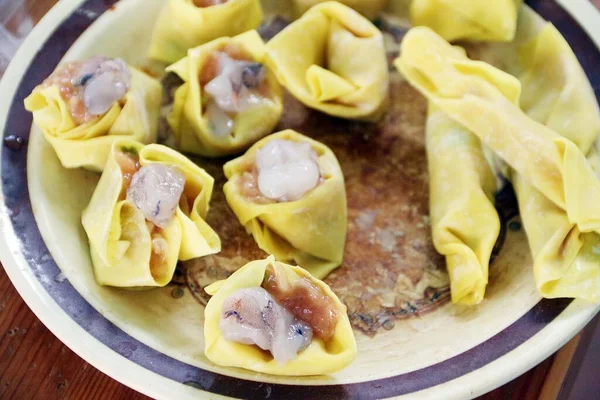 Çiğ ev yapımı hamur köfteleri karides ve domuz etinden yapılır ve buhar işleminden önce sarı unlarla sarılır.