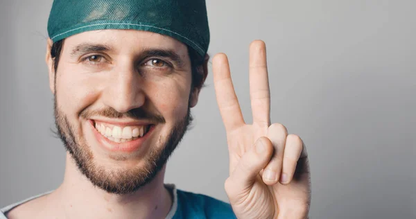 Joven Con Sombrero Médico Mirando Cámara Con Sonrisa Mostrando Paz — Foto de Stock