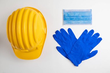 Covid konsept, sarı kask, tıbbi maske ve mavi lastik eldivenler. 