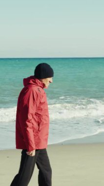 Ceketli Yaşlı Adam Deniz kenarında sakince yürüyor..