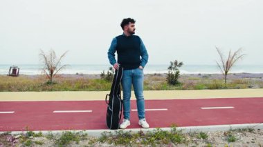 Müzisyen çantasında gitarıyla otobüsü bekliyor.. 