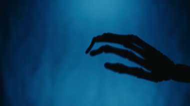 Sallanan El Silueti Cadılar Bayramı İskelet Mavi Arkaplan.