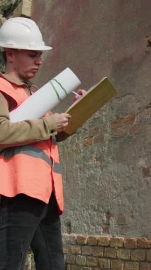 Mühendis, eski bina hakkında not almak için kalemi kullanıyor. . 