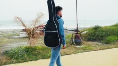 Gitarlı bir müzisyen açık hava konserine yetişmek için yürüyor.. 