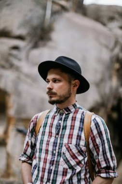 Dağlarda şapkalı yakışıklı bir hippi portresi.