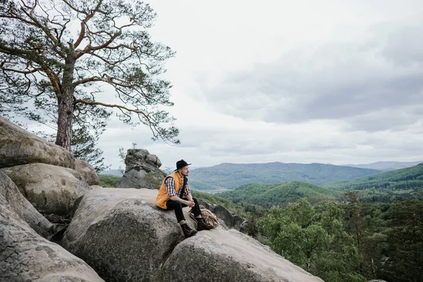 Recreation. A hiker climbs to the top of the mountain and enjoys the scenery