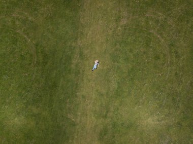 Gökyüzü manzaralı mutlu adam yeşil çimlerin üzerinde yatıyor ve gülümsüyor. Dinlenme ve yalnızlık kavramı
