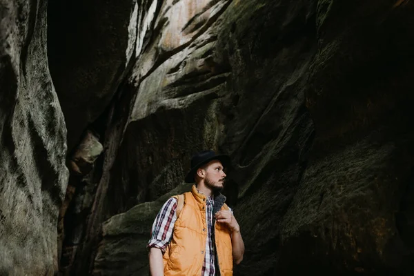 头戴帽子背着背包在山洞里的嬉皮士的人物形象 — 图库照片