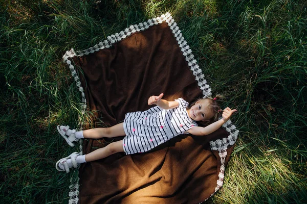 Gadis Kecil Berbaring Atas Selimut Antara Rumput Taman Dan Tersenyum — Stok Foto