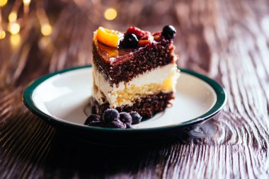 Bir parça kek krem çikolata meyve şekerli tatlı bokeh ışıkları ile ahşap arka plan üzerinde ile