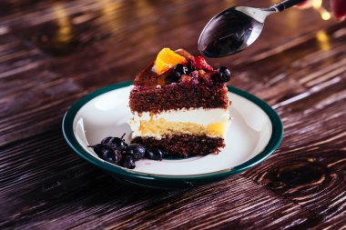 Bir parça kek krem çikolata meyve şekerli tatlı bokeh ışıklar ahşap zemin üzerine kaşıkla ile