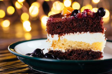 Bir parça kek krem çikolata meyve şekerli tatlı bokeh ışıkları ile ahşap arka plan üzerinde ile