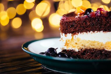 Bir parça kek krem çikolata meyve şekerli tatlı bokeh ışıkları ile ahşap arka plan üzerinde ile