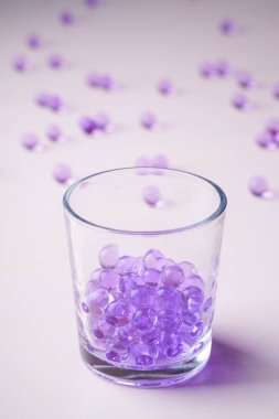 Beyaz arka plan üzerine dağınık mermerler ile şeffaf cam içme mor mermerler 