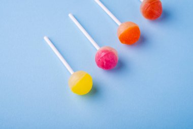 Mavi arka plan üst görünümünde çapraz satırda lolipop şekerler