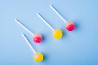 Mavi arka plan üst görünümünde dağınık lolipop şekerler