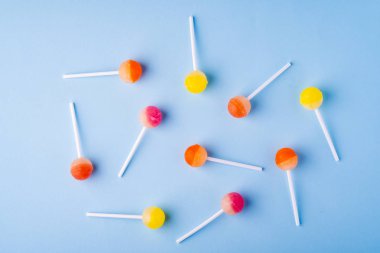 Mavi arka plan üst görünümünde dağınık lolipop şekerler